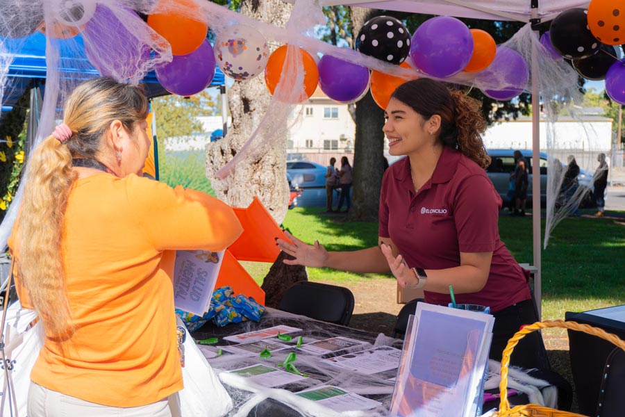 El Concilio staff member speaking with a community participant at an outreach event